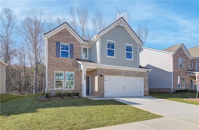 View of front of property featuring a garage and a front lawn
