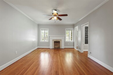 Unfurnished living room with ornamental molding, wood finished floors, a fireplace, and ceiling fan