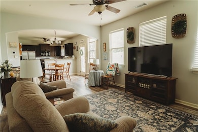 Living area featuring arched walkways, a ceiling fan, light wood-style floors, and baseboards