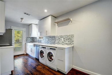 Laundry room featuring dark wood-type flooring, washer and dryer, and recessed lighting