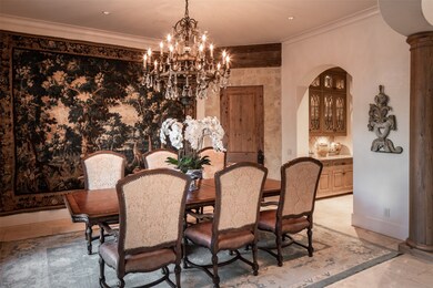 Dine alongside plaster walls, 11-foot ceilings, custom lighting, elegant millwork and integrated speakers in the formal dining room. Door with stone surround leads to wine room.