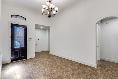 Entrance foyer with crown molding, a chandelier, and arched walkways