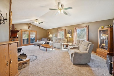 Spacious living room with vaulted ceilings, large windows, and a stunning stone fireplace centerpiece.