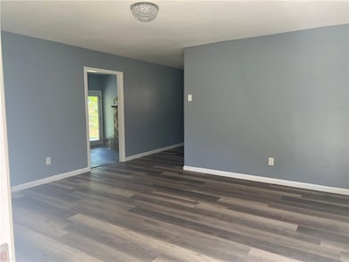 Unfurnished room featuring baseboards and dark woo