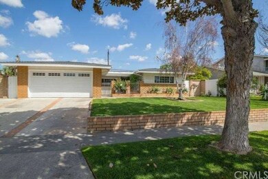Lush shade trees and blossoming flower beds enhance the beauty of the front yard