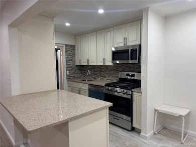 Kitchen featuring appliances with stainless steel finishes, tasteful backsplash, light stone counters, a peninsula, and recessed lighting
