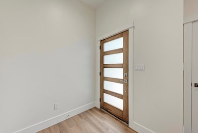 Foyer with light wood-style flooring and baseboar