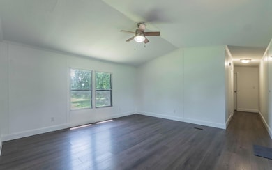 Empty room featuring ceiling fan, dark wood finis