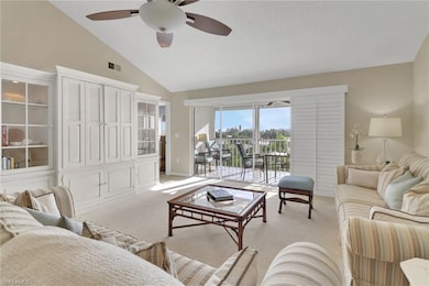 Carpeted living room with high vaulted ceiling and ceiling fan