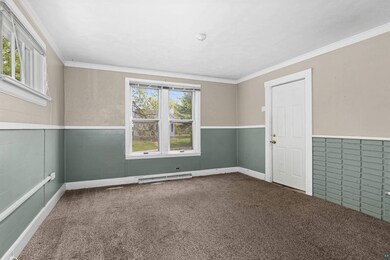Unfurnished room featuring carpet flooring, a wainscoted wall, crown molding, and baseboard heating