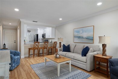 Living room with ornamental molding, light wood-style floors, and recessed lighting