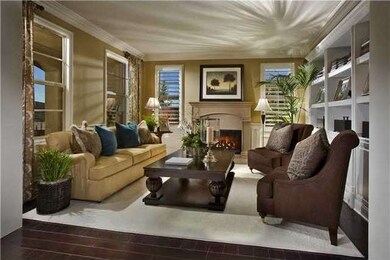 LIving room with wood burning gas fireplace, built in bookcases, shutters on side windows, trim around front windows, beautiful wood floors.