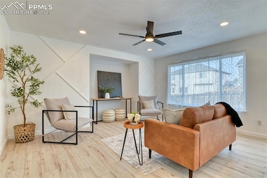 Living area featuring light wood-style floors, ceiling fan, recessed lighting, and a textured ceiling