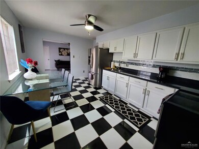 Kitchen featuring tile patterned floors, stainless steel fridge with ice dispenser, ceiling fan, dark countertops, and white cabinets