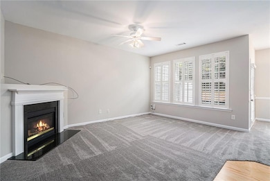 Unfurnished living room with a ceiling fan, a glass covered fireplace, and carpet