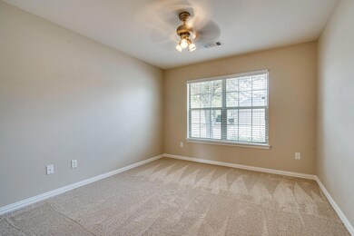 Empty room with carpet flooring, visible vents, ba