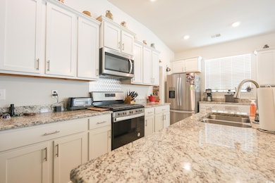 Kitchen with light stone countertops, visible vent