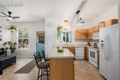 Kitchen featuring white appliances, updated lighting, a kitchen island, a kitchen breakfast bar, and open floor plan with updated lighting and ceiling fan