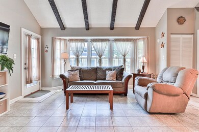 Tiled living room featuring vaulted ceiling with b