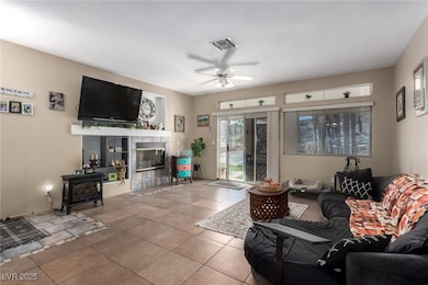 Tiled living area featuring a ceiling fan and a wood stove