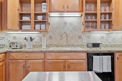Kitchen featuring black dishwasher, open shelves, tasteful backsplash, and light stone counters