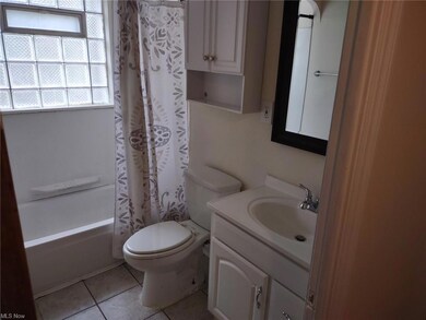 Full bathroom featuring tile floors, large vanity, toilet, and shower / bath combo