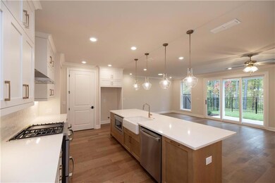 Kitchen featuring stainless steel appliances, a sink, wall chimney range hood, light wood-type flooring, and recessed lighting
