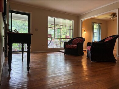 Living room featuring ornamental molding, wood-type flooring, and a ceiling fan