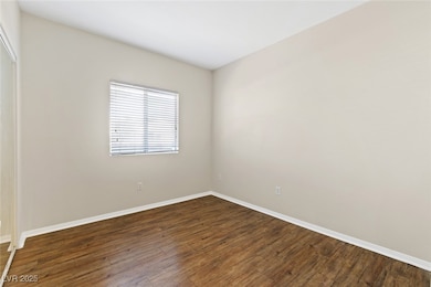 Empty room with dark wood-type flooring and baseboards