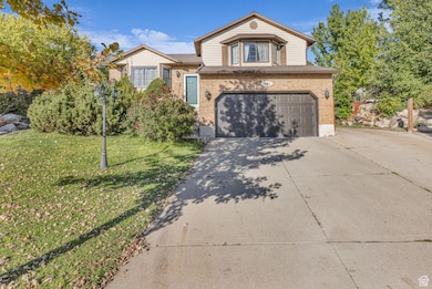 View of front of home with concrete driveway, brick siding, an attached garage, and a front yard