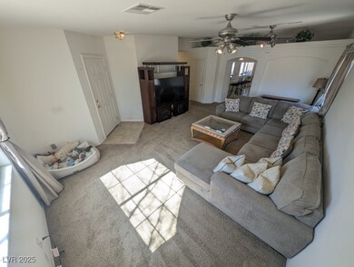 Living area featuring light carpet, ceiling fan, v