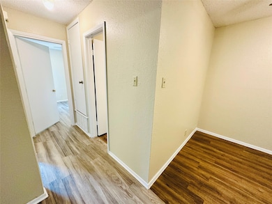 Hallway with a textured ceiling and wood finished