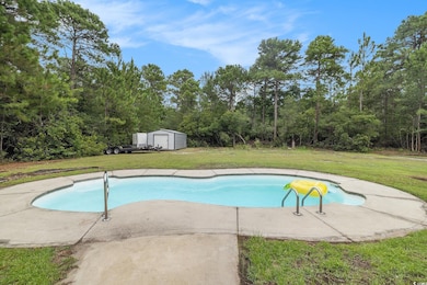 Swimming pool with a yard, a storage unit, and a patio