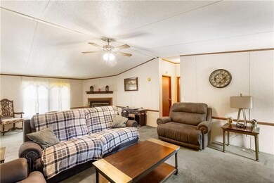 Living area featuring carpet flooring, vaulted ceiling, ceiling fan, and a fireplace