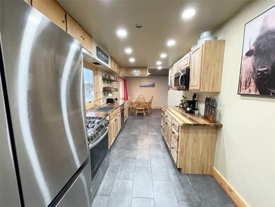Kitchen with appliances with stainless steel finishes, wooden counters, recessed lighting, light brown cabinets, and dark tile patterned floors