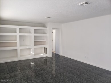Empty room with a textured ceiling, built in shelves, visible vents, and baseboards