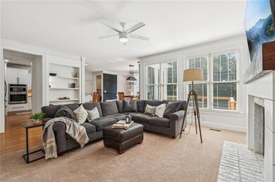 Living area featuring a ceiling fan, a fireplace, built in features, and light wood-style flooring