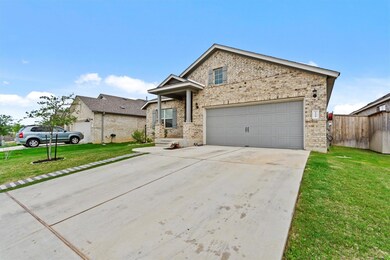 View of front facade featuring brick siding, driveway, and a garage