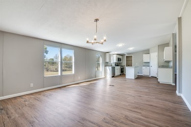 Unfurnished living room featuring light wood-style flooring, a chandelier, and a textured ceiling