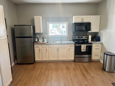 Kitchen with appliances: stainless steel finishes, white cabinets, and tasteful backsplash
