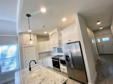 Kitchen featuring tile floors, white cabinets, stainless steel fridge, decorative backsplash, and granite counters