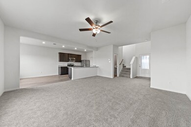 Unfurnished living room with light colored carpet, stairway, ceiling fan, and recessed lighting