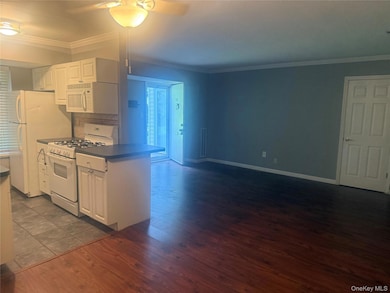 Kitchen with white cabinetry, crown molding, white gas range oven, dark wood-style floors, and ceiling fan