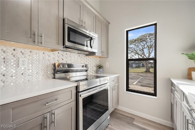 Kitchen with stainless steel appliances, light woo
