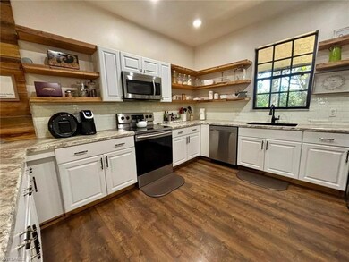 Kitchen featuring open shelves, tasteful backsplas