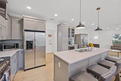 Kitchen with gray cabinetry, a kitchen breakfast bar, appliances with stainless steel finishes, open floor plan, and decorative backsplash