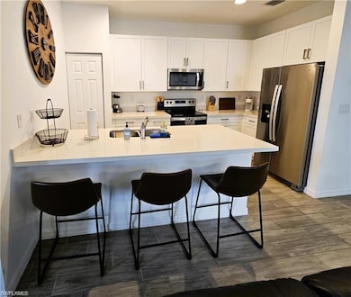 Kitchen featuring a kitchen bar, white cabinetry, 