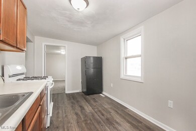Kitchen featuring brown cabinetry, white gas stove, freestanding refrigerator, and light countertops