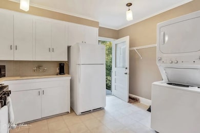 Kitchen featuring white cabinets, freestanding refrigerator, backsplash, ornamental molding, and gas range oven