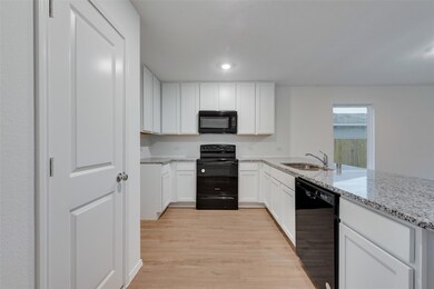 Kitchen with sink, black appliances, light wood-ty